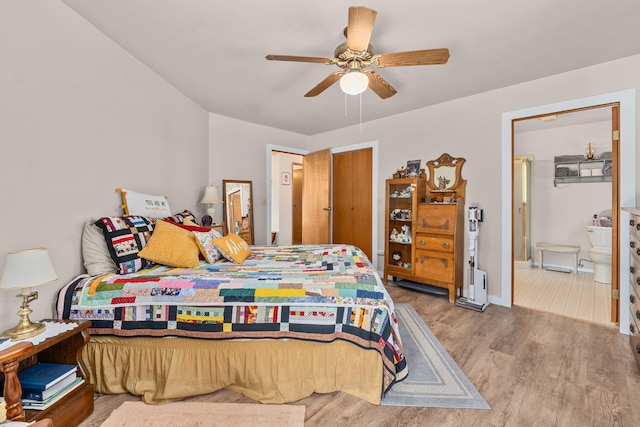 bedroom with baseboards, a ceiling fan, ensuite bath, and wood finished floors