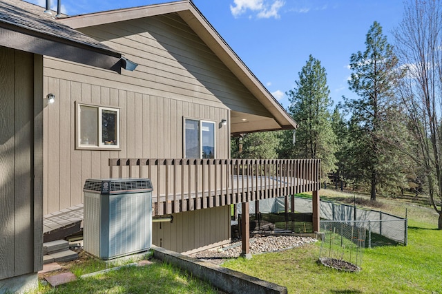 view of side of property with a yard, fence, a deck, and central air condition unit