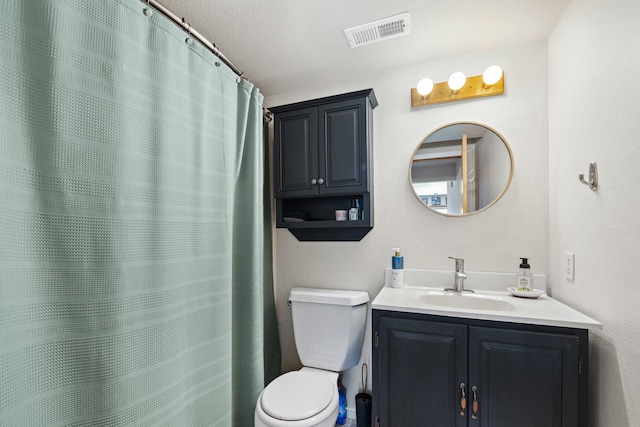 bathroom with toilet, vanity, and visible vents