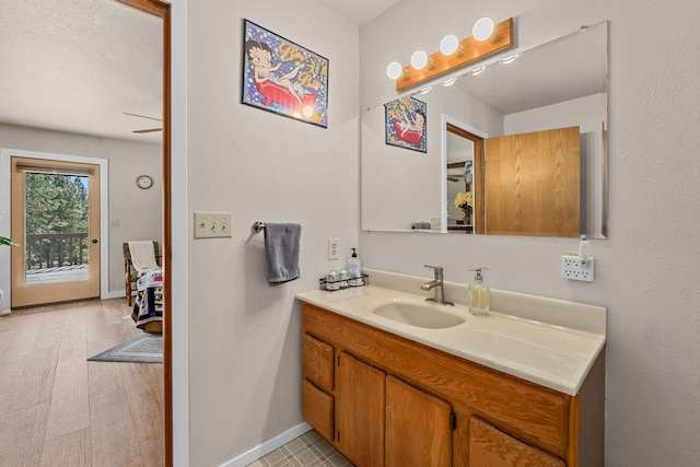bathroom with wood finished floors, vanity, and baseboards