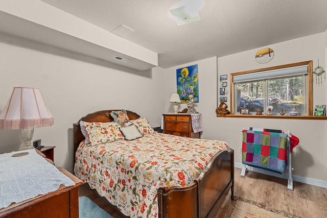 bedroom featuring visible vents, baseboards, and wood finished floors