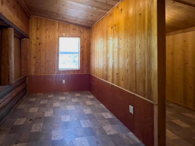 empty room with wood ceiling, tile patterned floors, vaulted ceiling, and wooden walls