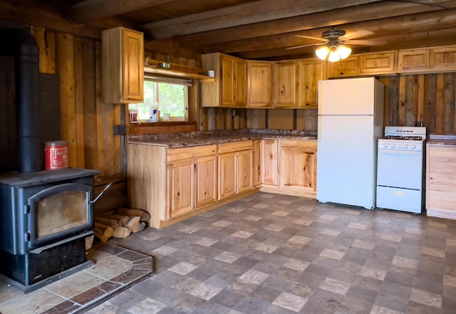 kitchen featuring beam ceiling, a ceiling fan, white appliances, wooden walls, and a wood stove
