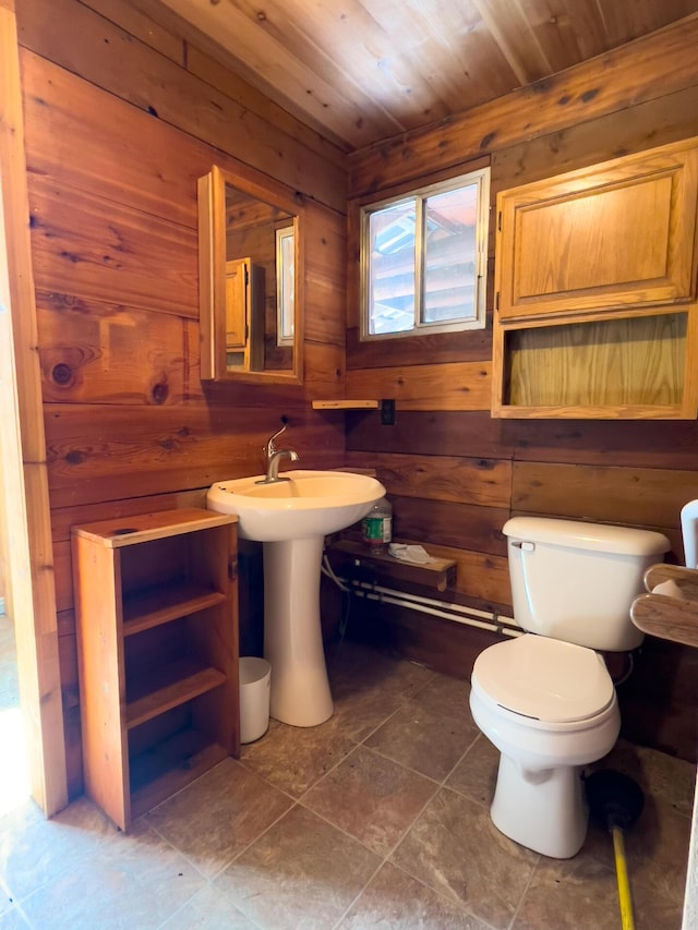half bathroom with tile patterned flooring, wood walls, wood ceiling, and toilet