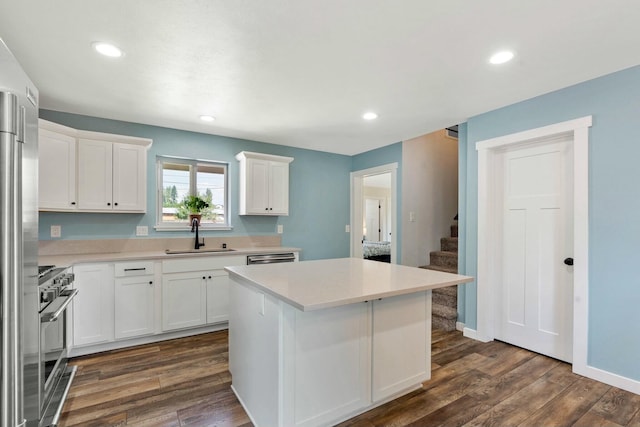 kitchen with white cabinets, light countertops, a sink, gas stove, and a center island