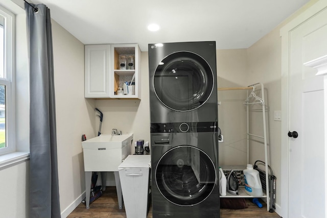 laundry room with recessed lighting, laundry area, wood finished floors, stacked washing maching and dryer, and baseboards