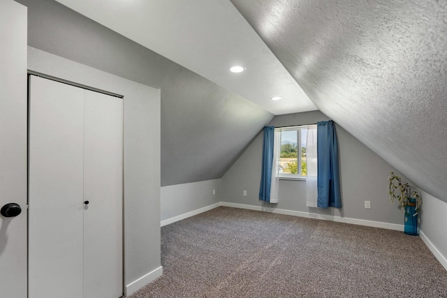 additional living space featuring baseboards, lofted ceiling, a textured ceiling, and carpet