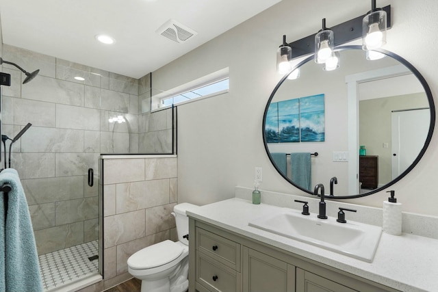 bathroom featuring toilet, a stall shower, visible vents, wood finished floors, and vanity