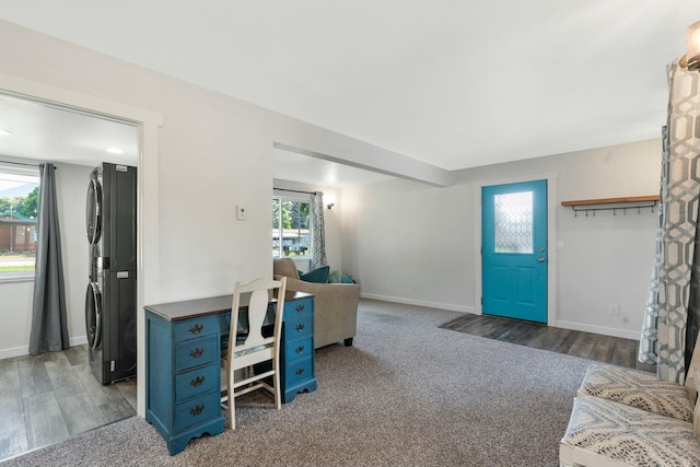 interior space featuring stacked washer / drying machine, wood finished floors, a wealth of natural light, and baseboards
