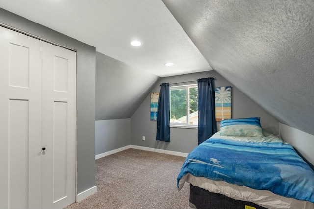bedroom featuring baseboards, lofted ceiling, a textured ceiling, and carpet