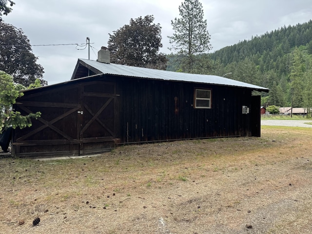 view of outdoor structure featuring a wooded view and an outbuilding