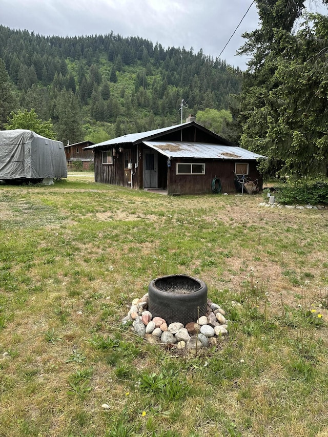 view of grassy yard with a forest view