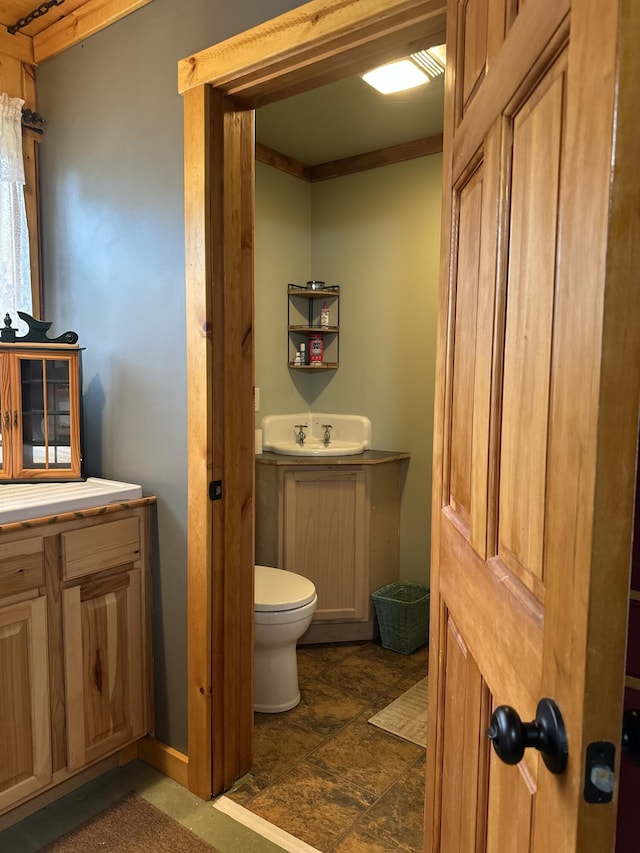 half bathroom with toilet, vanity, and stone finish flooring