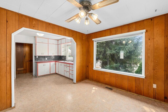 kitchen with white cabinets, a healthy amount of sunlight, and wooden walls