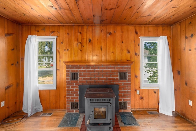 living room with light hardwood / wood-style floors, a wood stove, and wood walls