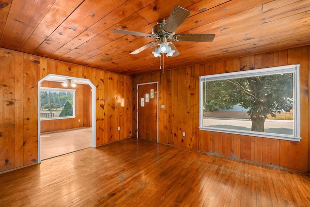 interior space featuring wood walls, light hardwood / wood-style floors, ceiling fan, and wood ceiling