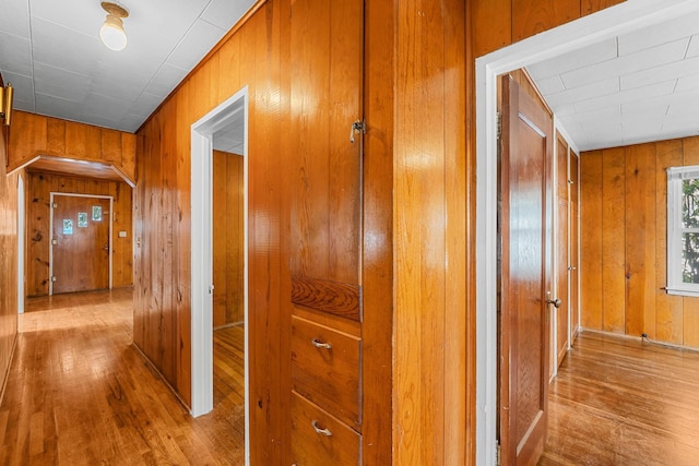 hall featuring light hardwood / wood-style flooring and wooden walls