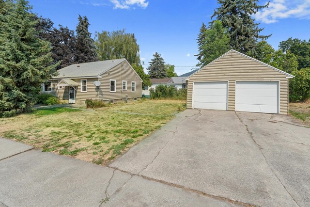 exterior space featuring a garage, an outbuilding, and a front lawn