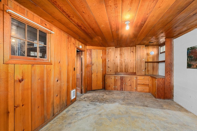 unfurnished room with concrete flooring, wood ceiling, and wooden walls