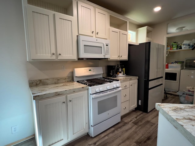 kitchen featuring washing machine and dryer, white cabinetry, white appliances, light countertops, and dark wood-type flooring