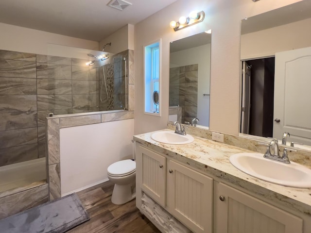 full bath with a walk in shower, wood finished floors, a sink, and visible vents