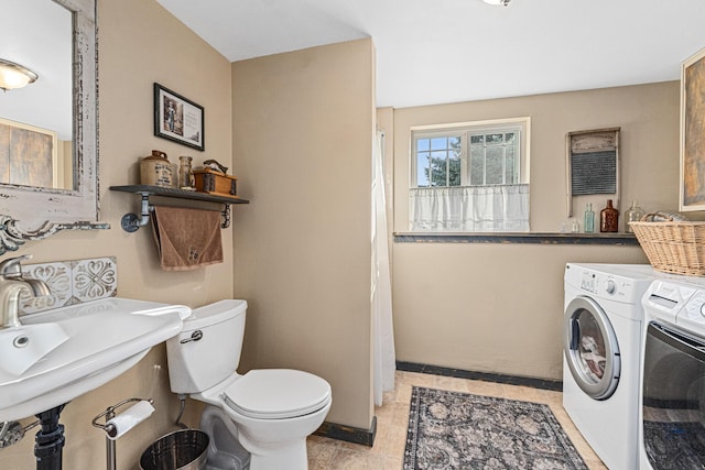 bathroom with washing machine and dryer, toilet, baseboards, a shower with shower curtain, and a sink