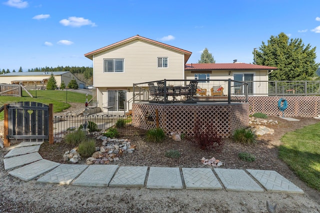 rear view of house featuring a wooden deck and fence