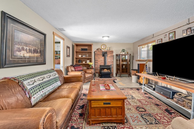 living room featuring visible vents, a wood stove, and a textured ceiling