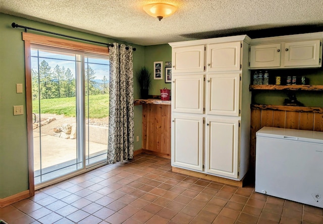 717 Conrad Hill Way, Colville, WA 99114 - kitchen featuring fridge, a textured ceiling, white cabinetry, tile patterned flooring, and baseboards