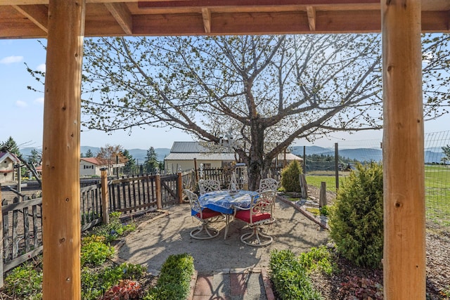 view of patio / terrace with fence, a mountain view, and outdoor dining space