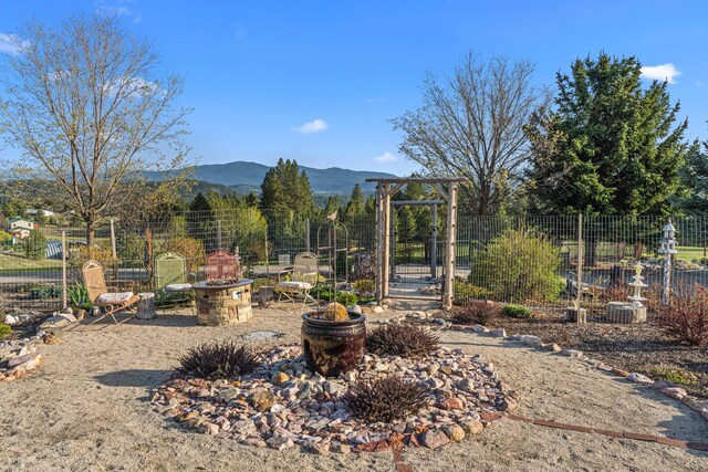 view of yard with an outdoor fire pit, a mountain view, and fence