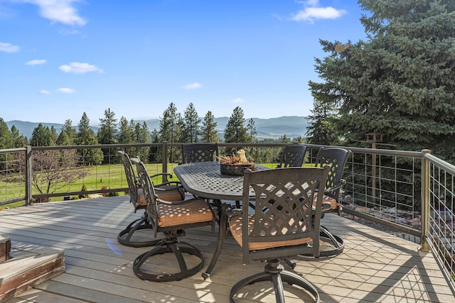 wooden deck with outdoor dining space and a mountain view