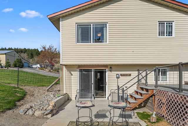 rear view of house featuring fence, a wooden deck, and a patio area