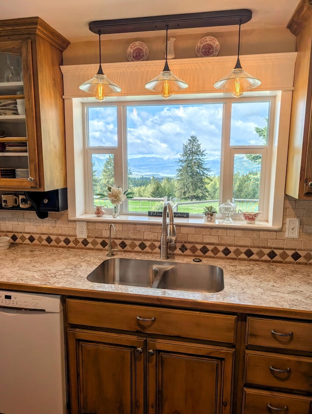 kitchen with white dishwasher, a sink, light countertops, decorative light fixtures, and decorative backsplash