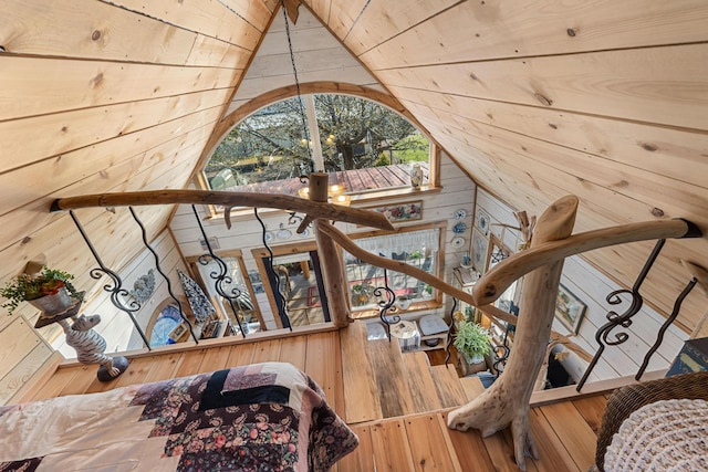 stairway featuring wooden walls, hardwood / wood-style flooring, and lofted ceiling