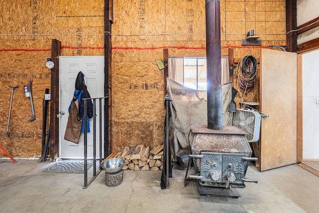 miscellaneous room with concrete flooring and a wood stove