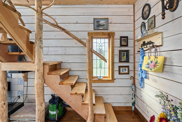 stairs featuring wooden walls and wood finished floors