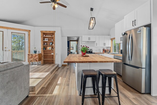 kitchen with a kitchen bar, appliances with stainless steel finishes, a sink, butcher block counters, and lofted ceiling
