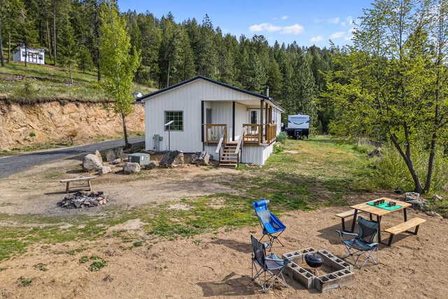 back of property featuring a view of trees and a fire pit