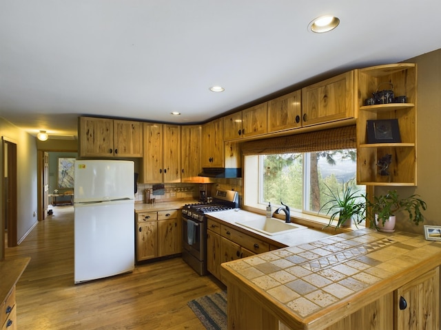 kitchen featuring sink, white refrigerator, tile countertops, and stainless steel range with gas stovetop