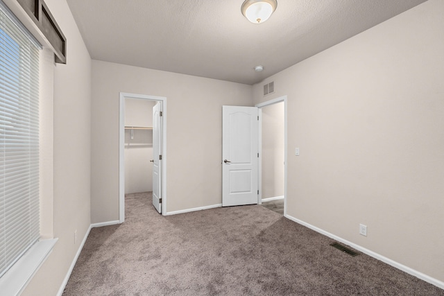 906 Valley Ave, Chewelah, WA 99109 - unfurnished bedroom featuring visible vents, carpet, a walk in closet, and baseboards