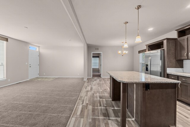 906 Valley Ave, Chewelah, WA 99109 - kitchen with stainless steel refrigerator with ice dispenser, a center island, open shelves, dark brown cabinets, and baseboards