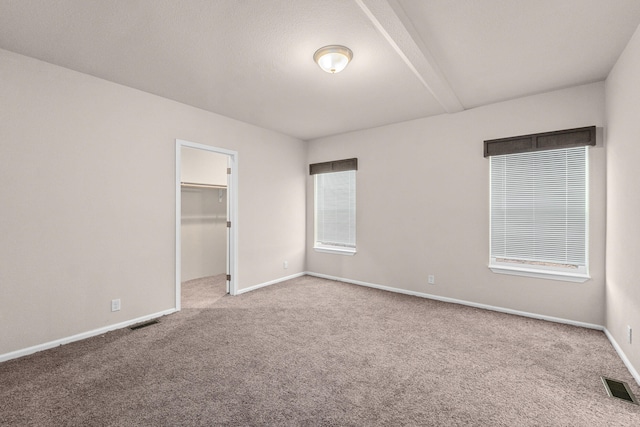 906 Valley Ave, Chewelah, WA 99109 - unfurnished bedroom featuring a walk in closet, baseboards, carpet, and visible vents