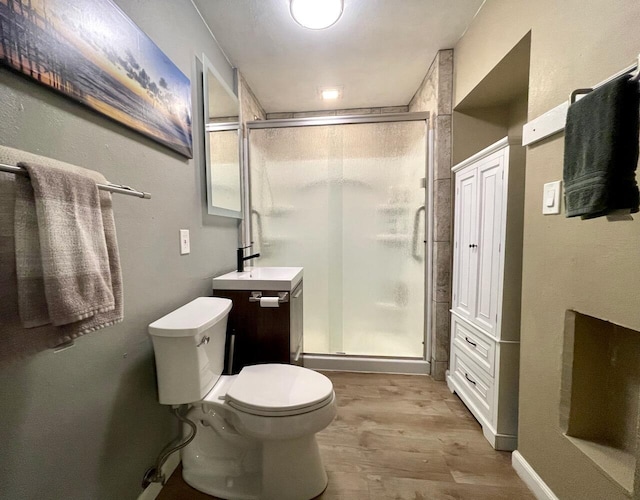 bathroom featuring hardwood / wood-style flooring, an enclosed shower, and toilet