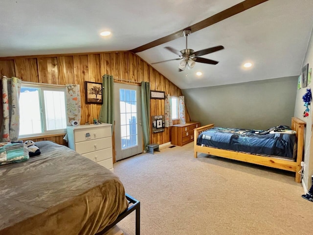 carpeted bedroom with ceiling fan, wood walls, and vaulted ceiling