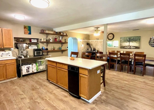 kitchen with ceiling fan, a center island, a breakfast bar area, and light wood-type flooring