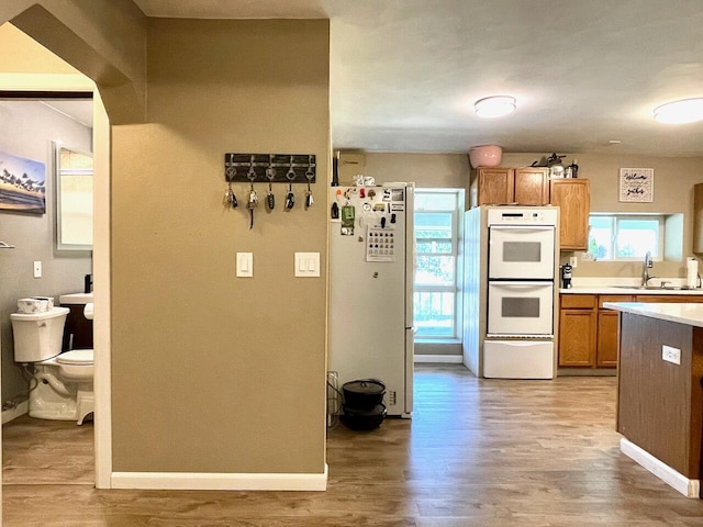 kitchen with wood-type flooring, sink, and white appliances