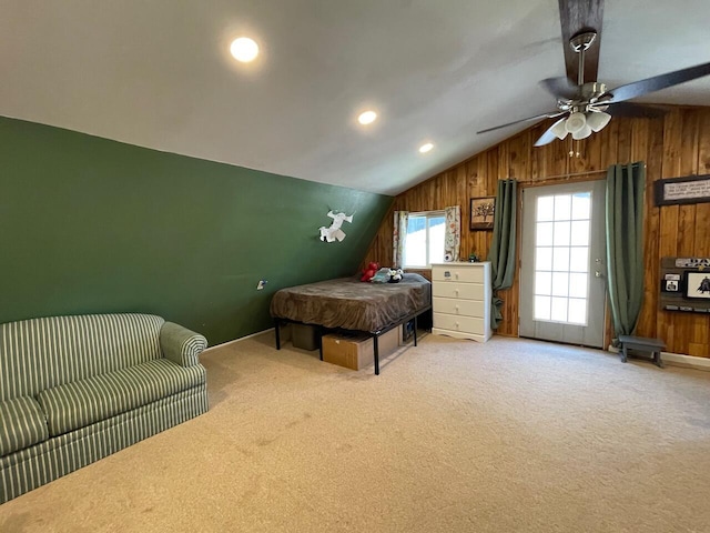 bedroom with carpet flooring, wooden walls, vaulted ceiling, and ceiling fan