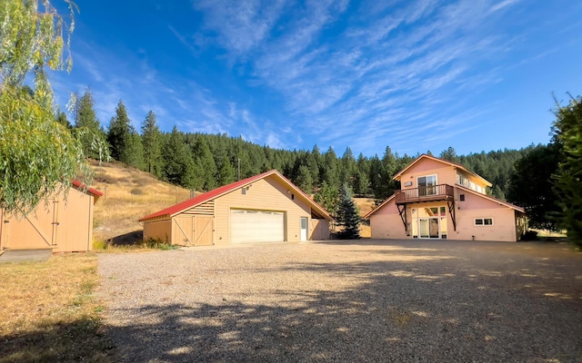 view of front of home with an outbuilding, driveway, a wooded view, and a garage