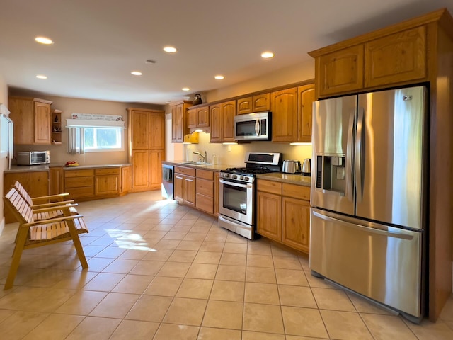 kitchen featuring stainless steel appliances, brown cabinetry, a sink, and light tile patterned floors